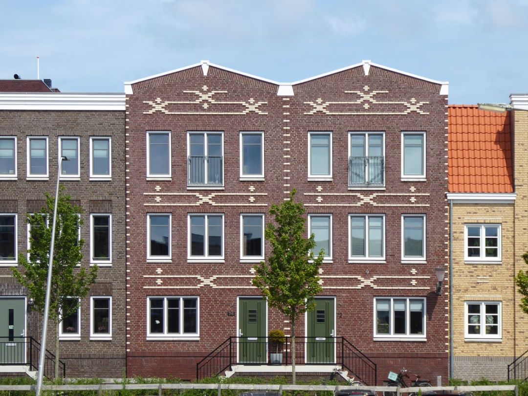 Reihe fertiggestellter Wohnhäuser mit Klinkerfassade, hellen Fenstern und Vorgärten
